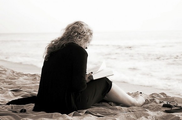 海で読書をする女性